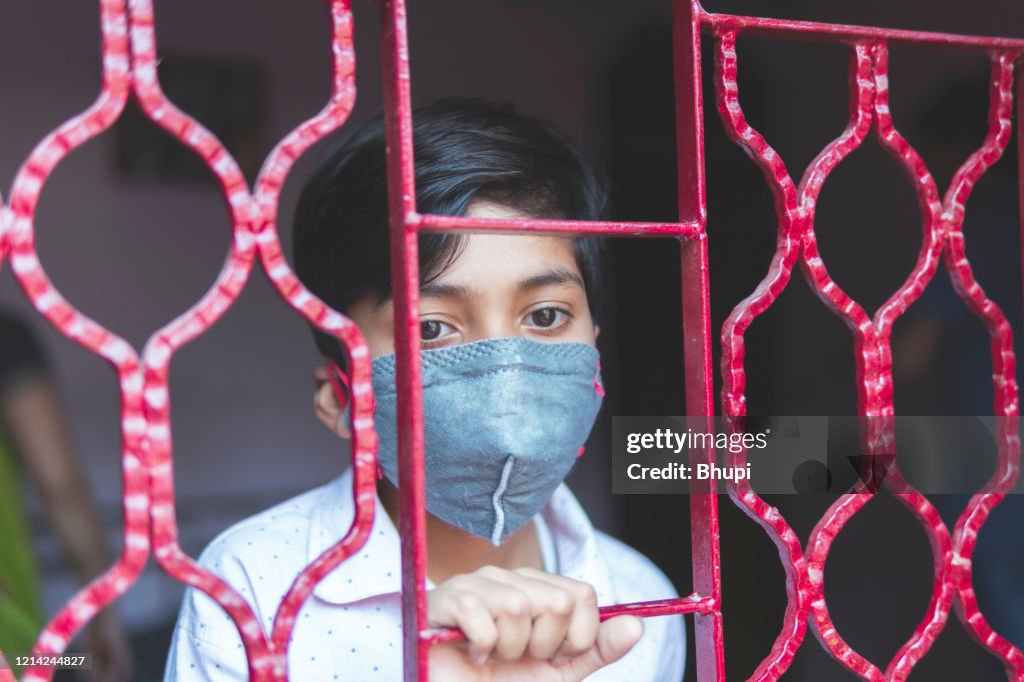Der traurige Junge schützt sich und trägt eine Maske gegen das Corona-Virus