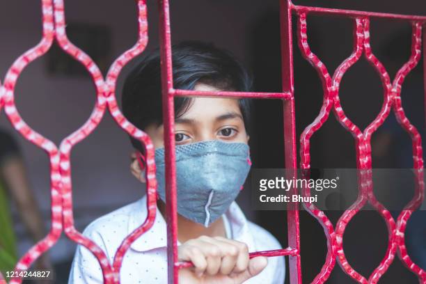 the sad boy is protecting herself and wearing a mask against the corona virus - lockdown stock pictures, royalty-free photos & images