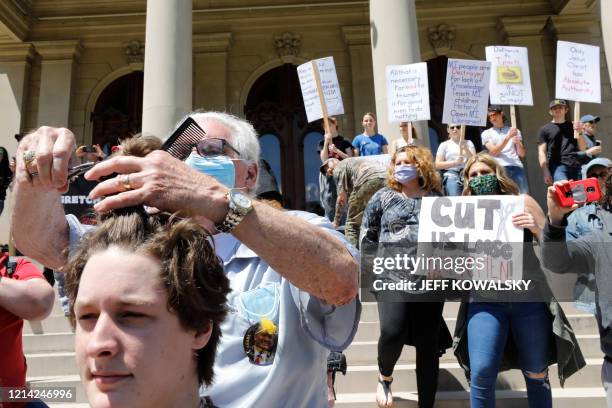 Barber Karl Manke cuts hair at the Michigan Conservative Coalition organized "Operation Haircut" outside the Michigan State Capitol in Lansing,...
