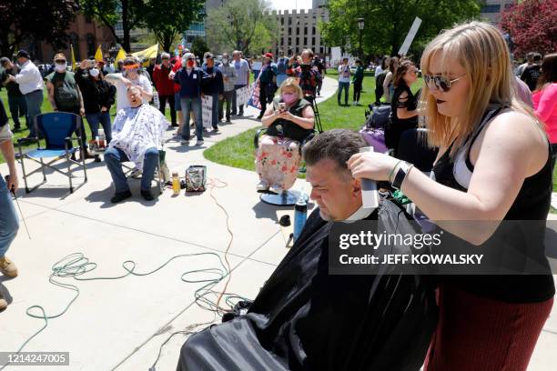 People get their hair cut at the Michigan Conservative Coalition organized "Operation Haircut" outside the Michigan State Capitol in Lansing,...