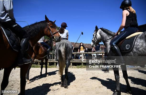 French Sports Minister Roxana Maracineanu wearing a protective mask looks at children who have taken up horseback riding at the riding school on May...