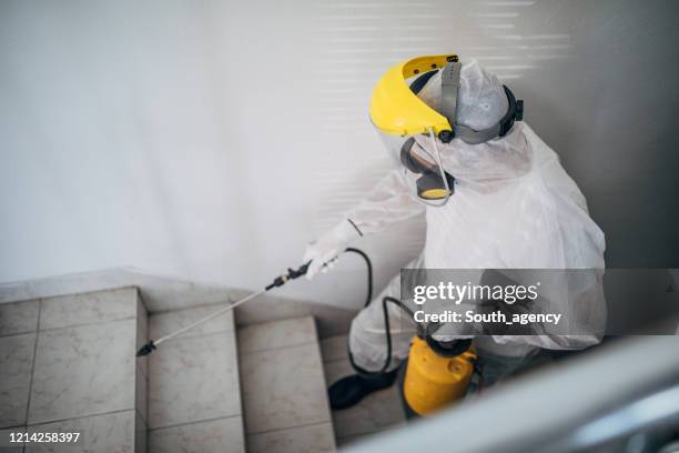 homme dans le costume protecteur désinfectant des étapes dans le bâtiment - combinaison de protection photos et images de collection