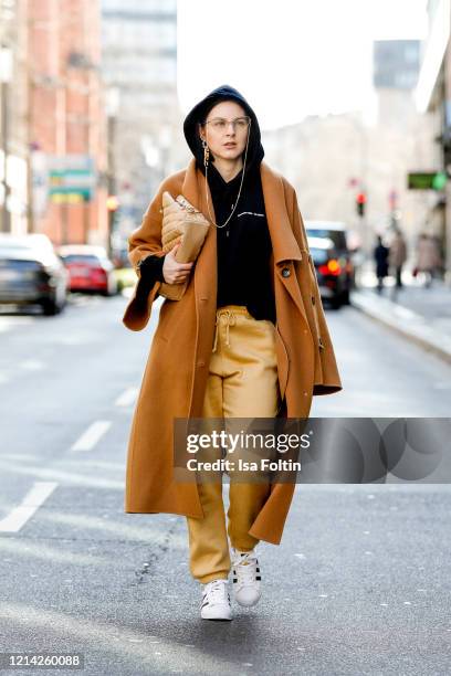 Influencer Maria Barteczko, wearing a brown wool coat by Blancore, a black hoodie by Soulland, yellow jogging pants by Missguided, white Superstar...