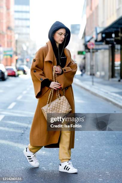 Influencer Maria Barteczko, wearing a brown wool coat by Blancore, a black hoodie by Soulland, yellow jogging pants by Missguided, white Superstar...