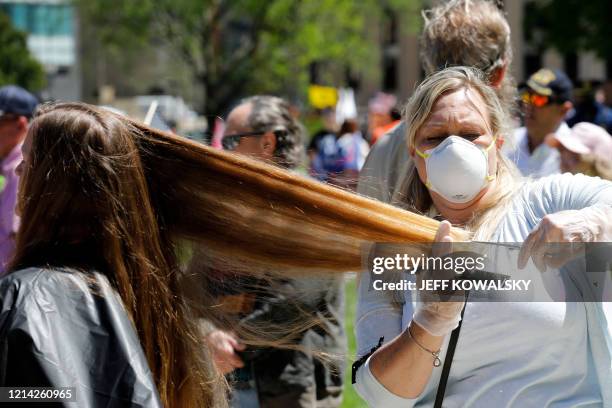 Randi Bates cuts hair during the Michigan Conservative Coalition organized "Operation Haircut" outside the Michigan State Capitol in Lansing,...