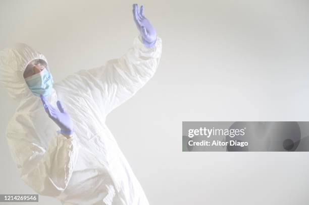 man or scientist in danger, trying to protect himself from something with his hands. he is wearing a mask, gloves and glasses and protective suit (hazmat suit). - scientist and explosion stock pictures, royalty-free photos & images