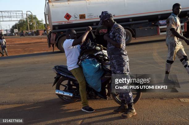 Policeman searches a vendor on a motorbike in Cinkasse, the northern Togo commercial border post with Burkina Faso, on February 16, 2020. - Togolese...