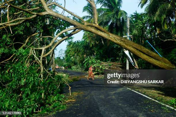 Woman removes debris from a road after the landfall of cyclone Amphan in Midnapore, West Bengal, on May 21, 2020. - The strongest cyclone in decades...