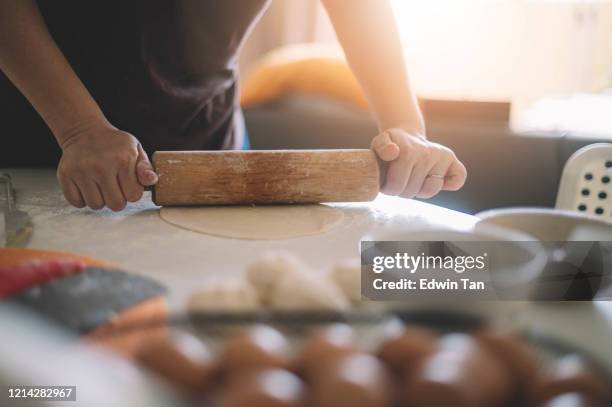 an asian chinese house wife preparing food using rolling pin with flour mixed with eggs on table making dough - rolling pin stock pictures, royalty-free photos & images