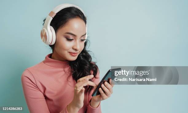 happy teenage beautiful girl use mobile phone to open the music song from smartphone application. technology concept - portrait of a musician stock pictures, royalty-free photos & images