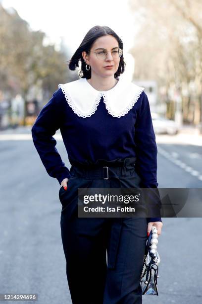 Influencer Maria Barteczko, wearing a blue cashmere knit, a white poplin blouse with big collar and black high waisted pants by Arket, red leather...