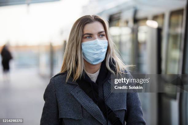 young woman outside train station wearing a virus protective face mask - commuter mask stock pictures, royalty-free photos & images