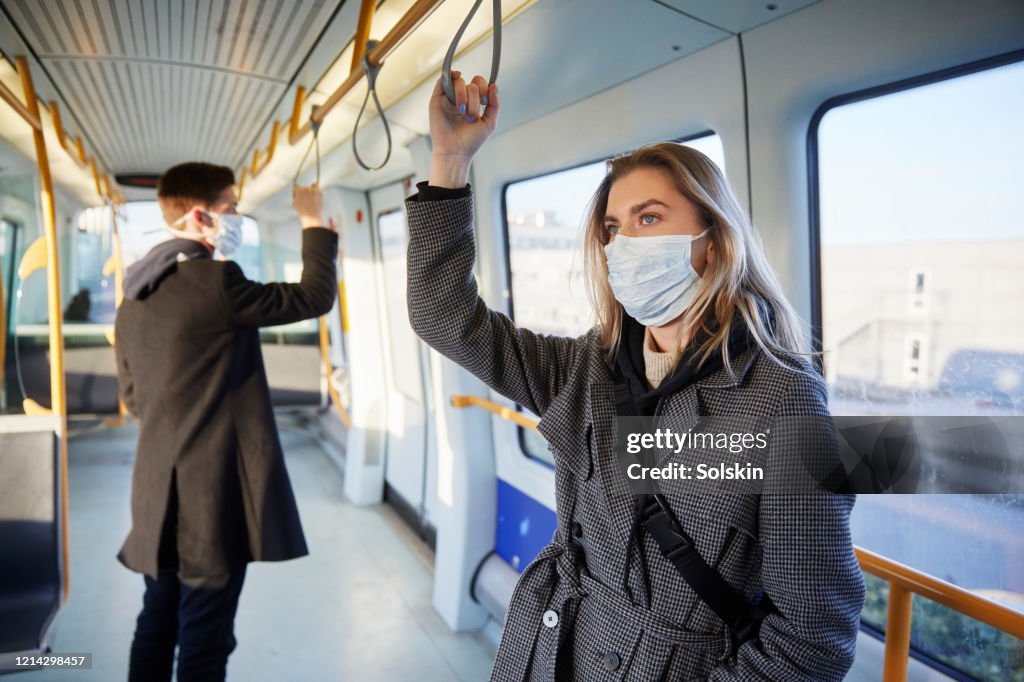 Young woman inside train, wearing a virus protective face mask