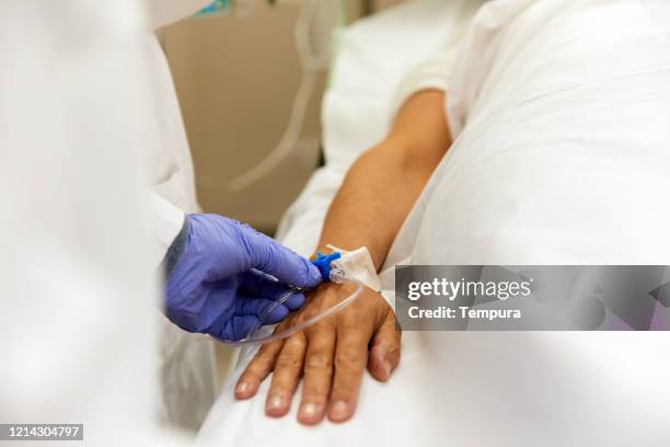 close up view of a doctors and nurses applying an intravenous drip on a patient. - iv drip womans hand stock pictures, royalty-free photos & images