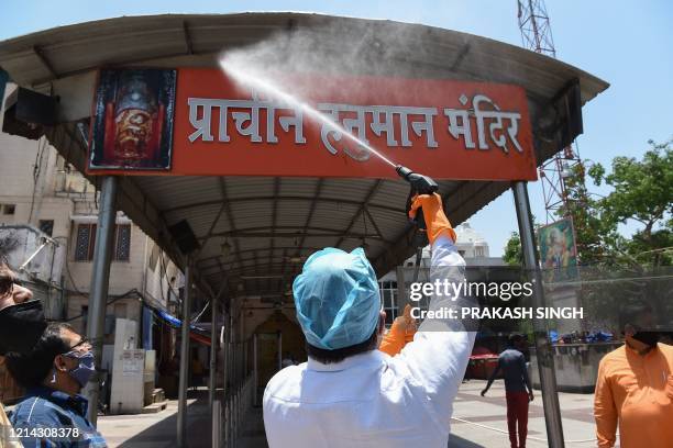 Volunteer of the Vishwa Hindu Parishad and Bajrang Dal sanitises the Hanuman temple after the government eased restrictions as a preventive measure...