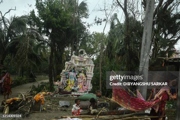 Resident hangs a saree for drying as kids play near a damaged Hindu idol following the landfall of cyclone Amphan in Khejuri area of Midnapore, West...