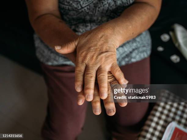 cu : femme aînée appliquant le désinfectant de main dans le salon à la maison. - se frotter les mains photos et images de collection