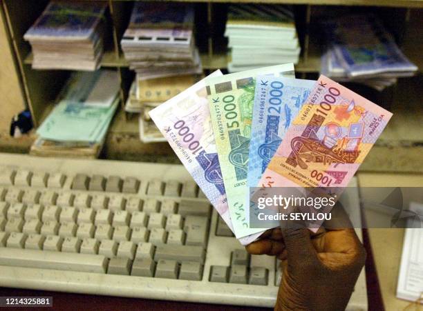 Bank employee holds new banknote of 10000 2000 and 1000 CFA francs in exchange on the first day of a 40 million euro campaign to replace old...