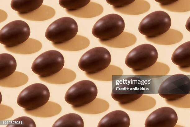 de eieren van de chocolade in een rij op gele achtergrond - easter pattern stockfoto's en -beelden