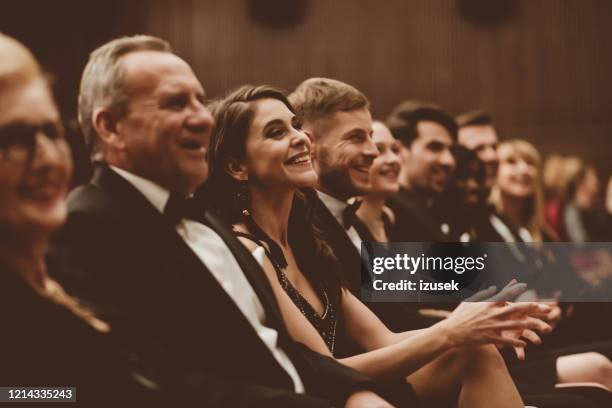 smiling audience sitting in the theater - gala dress stock pictures, royalty-free photos & images