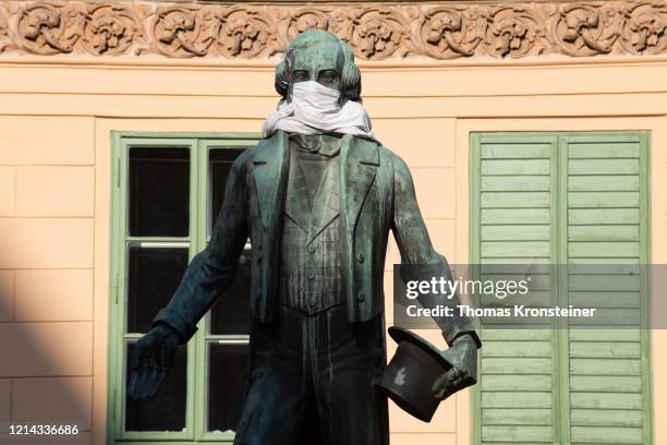 The statue of Johann Nestroy adorned with a protective mask on March 23 in Vienna, Austria. The coronavirus and the disease it causes, covid-19, are...