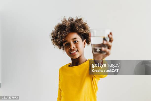 young girl holding a glass of water - children water stock pictures, royalty-free photos & images