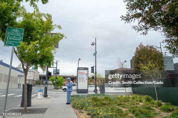 Medical provider in scrubs stands near a sign outside the University of California San Francisco medical center in Mission Bay during an outbreak of...