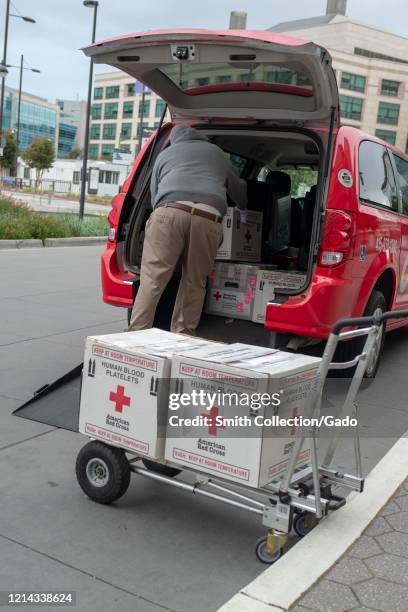 Person loads boxes labeled Red Cross Human Blood Platelets into a vehicle at the entrance of the University of California San Francisco medical...