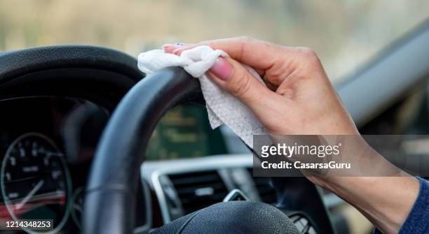 female driver sanitising the steering wheel with a wet wipe - rubbing stock pictures, royalty-free photos & images