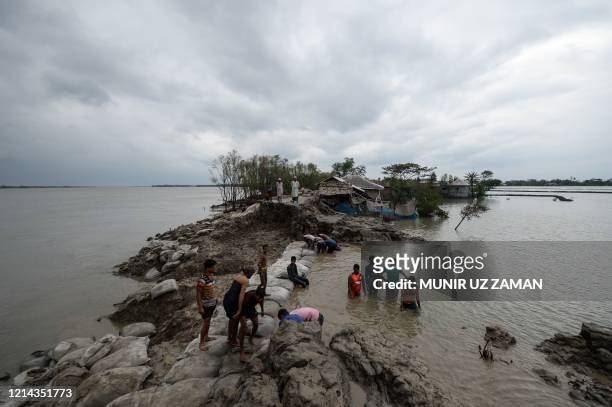 Volunteers and residents work to repair a damaged dam following the landfall of cyclone Amphan in Burigoalini on May 21, 2020. - At least 84 people...