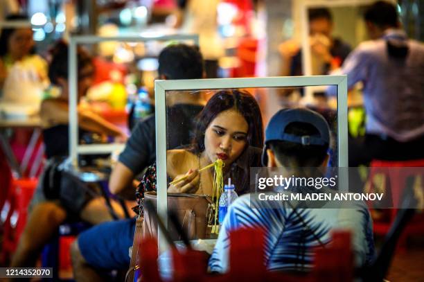People eat at a street restaurant implementing social distancing with plastic dividers after the Thai government relaxed measures to combat the...