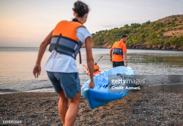 friends carrying kayak to water - carrying kayak stock pictures, royalty-free photos & images