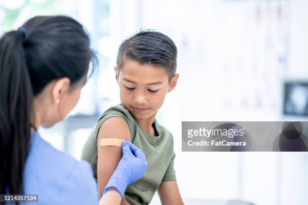 young boy visits doctor - flu vaccine stock pictures, royalty-free photos & images