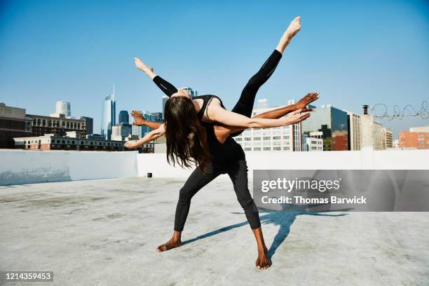 woman balancing on dance partners back while performing on rooftop overlooking city - free show stock pictures, royalty-free photos & images