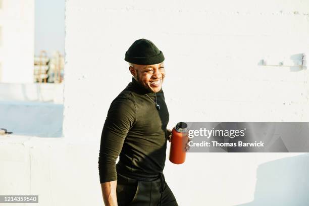 smiling man with reusable water bottle relaxing after rooftop yoga class - black and white photo out door sport photos et images de collection