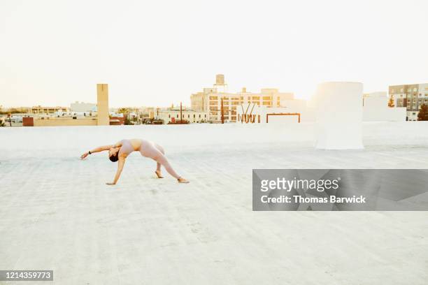 Woman doing yoga on rooftop at sunset