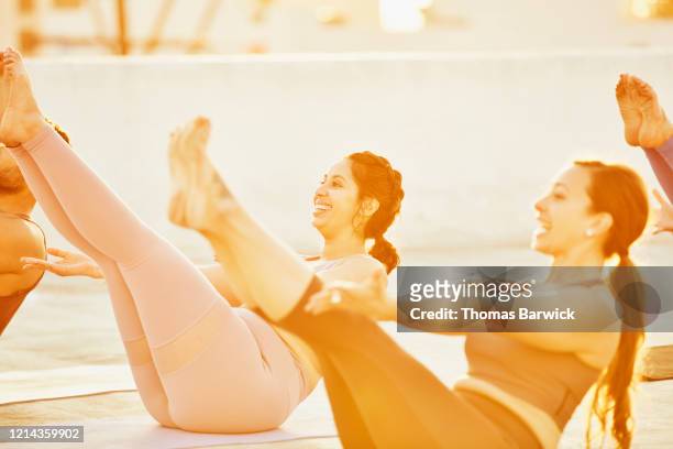 Smiling woman in boat pose during rooftop yoga class