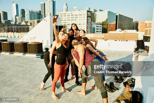 smiling friends taking group selfie after rooftop yoga class - friendly match stockfoto's en -beelden