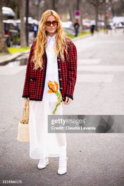 Blanca Miro Scrimieri, wearing a white shirt, white decorated long dress, red and black checked jacket, rattan bag, white socks and white sandals, is...