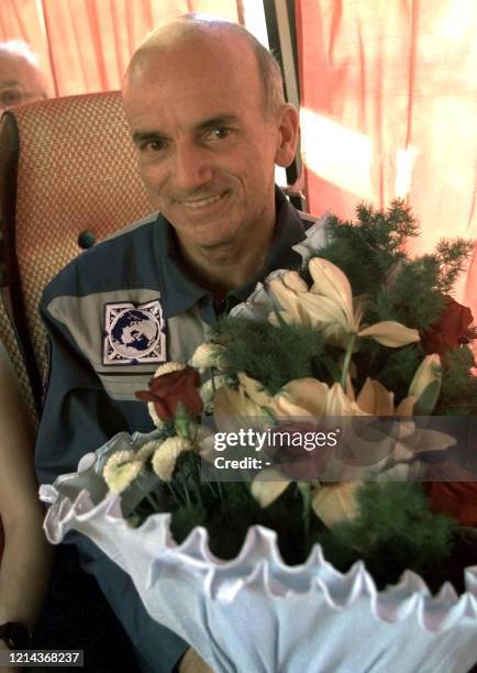 The world's first space tourist US Dennis Tito smiles as he holds flowers inside a bus driving him from the airport to the Star City outside...