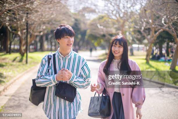 young couple walking in public park in sunny day - japanese couple stock pictures, royalty-free photos & images