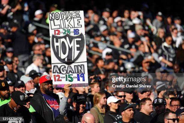 Fans in the stands hold signs during the first half between the Oakland Raiders and the Jacksonville Jaguars at RingCentral Coliseum on December 15,...