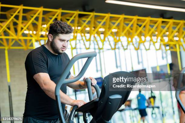 latino-mann mit durchschnittsalter von 29 jahren bei elliptischen übungen - 25 29 years stock-fotos und bilder