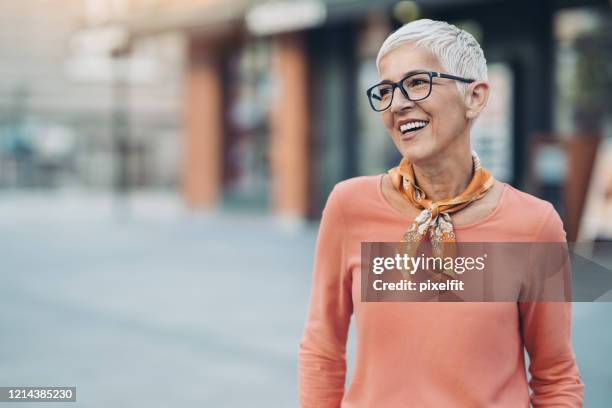 lächelnde reife frau mit kurzen haaren und brille - brillen stock-fotos und bilder