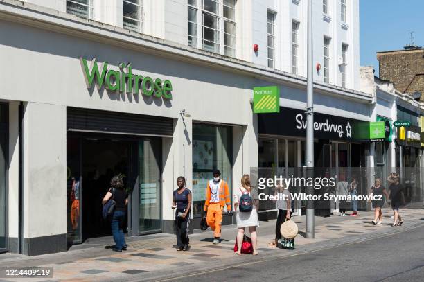 People observe social distancing as they queue in front of Waitrose supermarket in Battersea, south-west London on 21 May, 2020 in London, England....