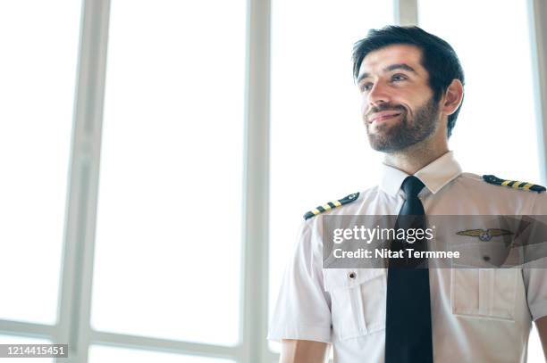 shot of handsome young pilot standing inside of airport building. - beard pilot stock pictures, royalty-free photos & images