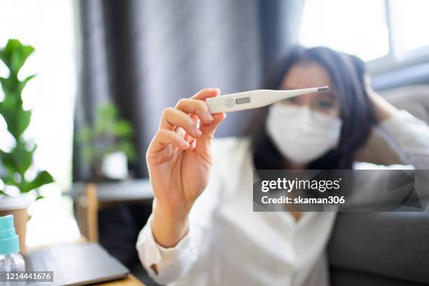 asian female use thermometer checking temperature for fever or covid-19 (corona virus) and  coronavirus outbreak 14 day at home - digital thermometer stock pictures, royalty-free photos & images