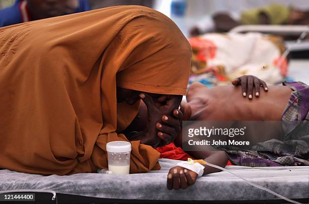 An exhausted mother stays by her malnourished son's side in a Turkish field hospital on August 19, 2011 in Mogadishu, Somalia. The tented hospital,...