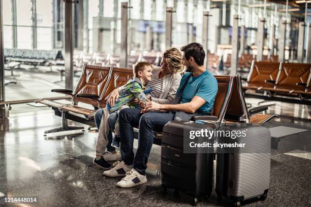 happy family talking while waiting their transportation on a station. - family airport stock pictures, royalty-free photos & images