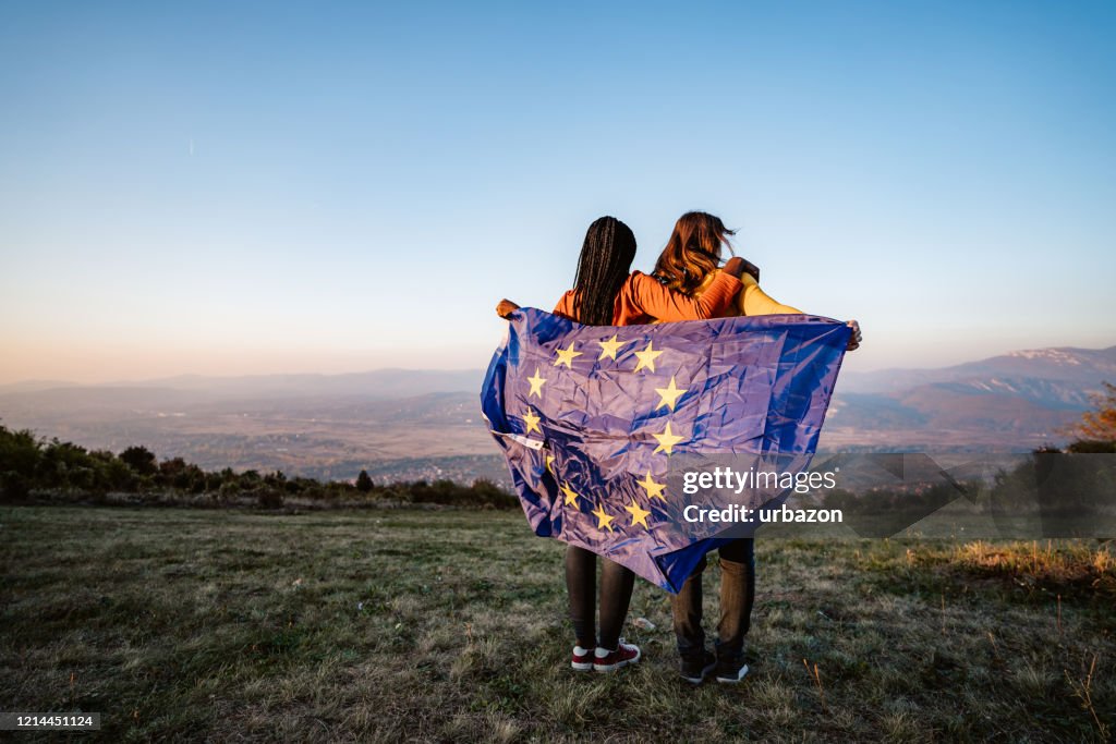 Dos mujeres multiétnicas que ostenten la bandera de la Unión Europea